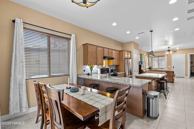 kitchen featuring light stone countertops, light tile patterned floors, a peninsula, and appliances with stainless steel finishes