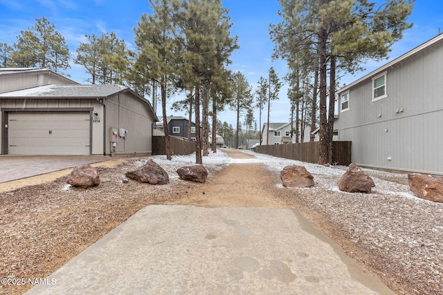 view of yard with a residential view, decorative driveway, fence, and an attached garage