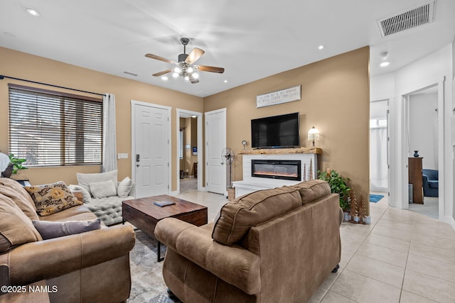 living area with a glass covered fireplace, visible vents, recessed lighting, and light tile patterned flooring