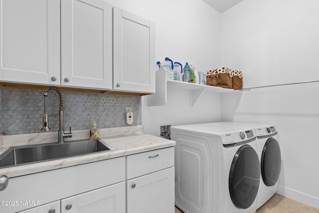 laundry area featuring washing machine and clothes dryer, light tile patterned floors, cabinet space, a sink, and baseboards