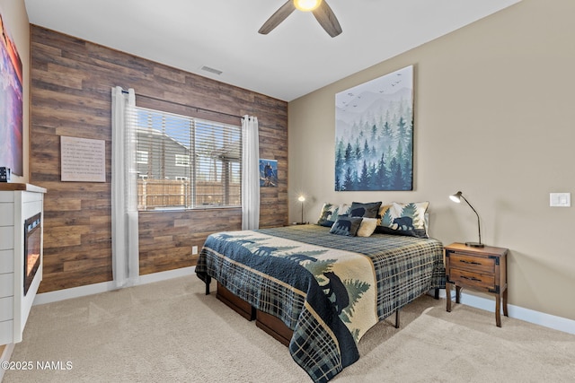 carpeted bedroom featuring wood walls, a fireplace, baseboards, and a ceiling fan