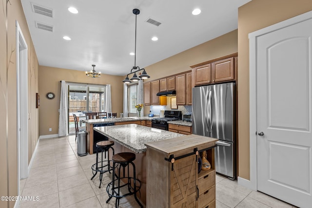 kitchen with light stone counters, light tile patterned flooring, a peninsula, black appliances, and a kitchen bar