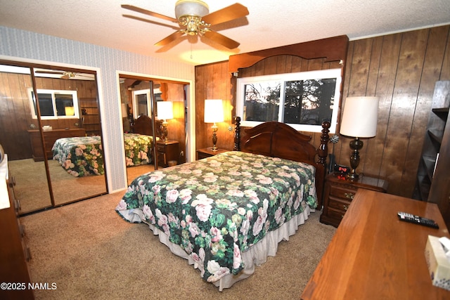 733 S 3rd St, Williams, AZ 86046 - bedroom with carpet floors, two closets, a textured ceiling, wooden walls, and wallpapered walls