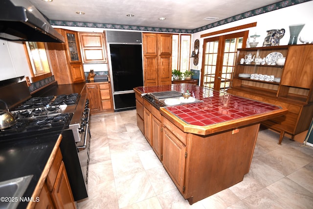 733 S 3rd St, Williams, AZ 86046 - kitchen with built in fridge, tile counters, under cabinet range hood, brown cabinets, and french doors