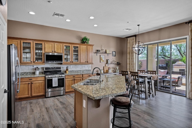 41215 N Lytham Ct, Phoenix, AZ 85086 - kitchen with appliances with stainless steel finishes, a sink, brown cabinets, wood finished floors, and tasteful backsplash