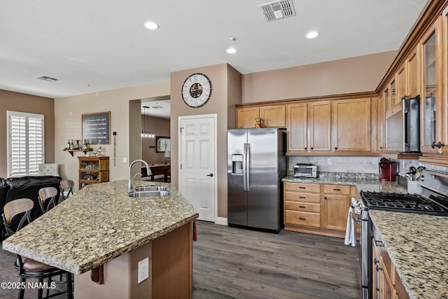 41215 N Lytham Ct, Phoenix, AZ 85086 - kitchen with appliances with stainless steel finishes, a sink, dark wood-style flooring, a kitchen bar, and light stone counters