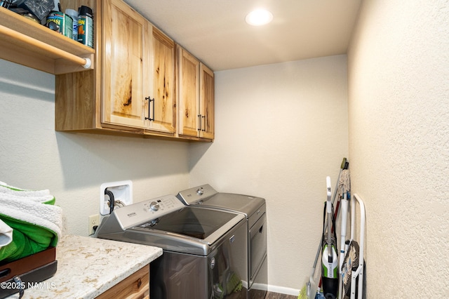 clothes washing area featuring cabinets and separate washer and dryer