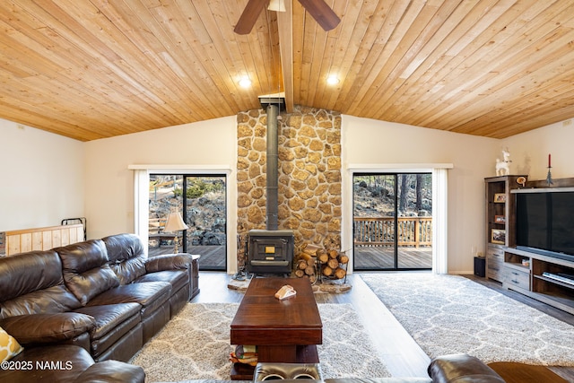 living room featuring hardwood / wood-style flooring, a healthy amount of sunlight, vaulted ceiling with beams, and a wood stove