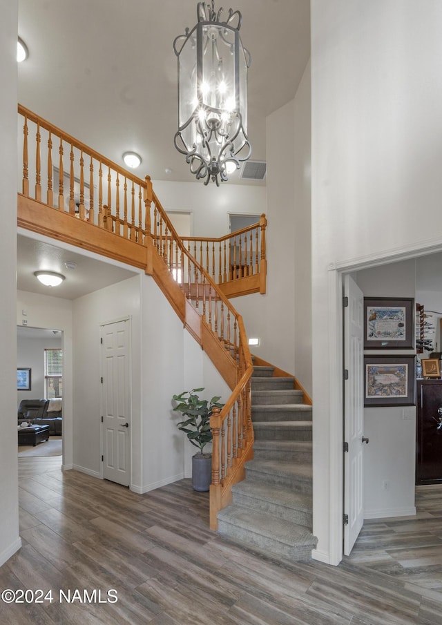 staircase featuring hardwood / wood-style flooring and a notable chandelier