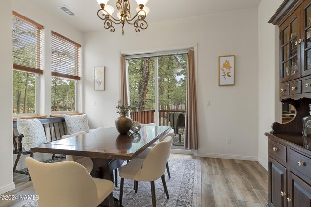 dining area with a healthy amount of sunlight, light hardwood / wood-style flooring, and an inviting chandelier