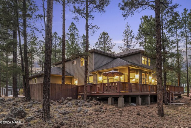 back house at dusk featuring a wooden deck