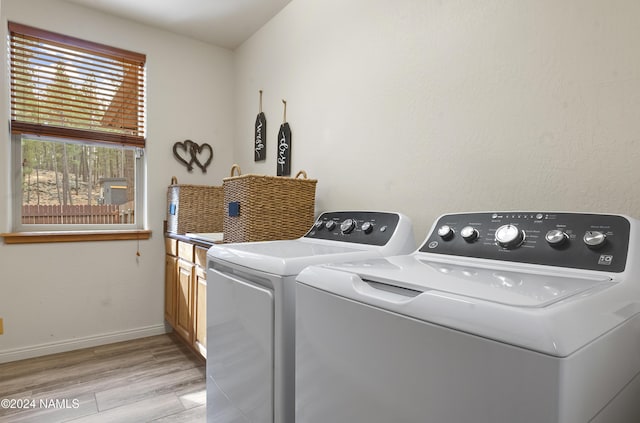 laundry room with separate washer and dryer, light hardwood / wood-style flooring, and cabinets