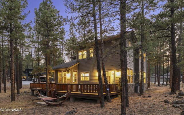 back house at dusk featuring a wooden deck