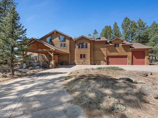 155 E Moonrise Vly, Flagstaff, AZ 86001 - view of front of property with concrete driveway, an attached garage, roof mounted solar panels, and stone siding