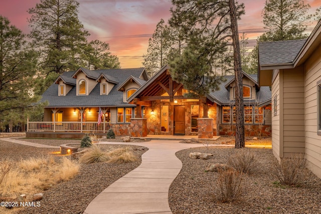 exterior space with stone siding, a porch, and a shingled roof