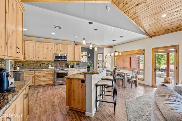 7507 Deville Ln, Flagstaff, AZ 86004 - kitchen with appliances with stainless steel finishes, light brown cabinets, vaulted ceiling, backsplash, and light wood-style flooring
