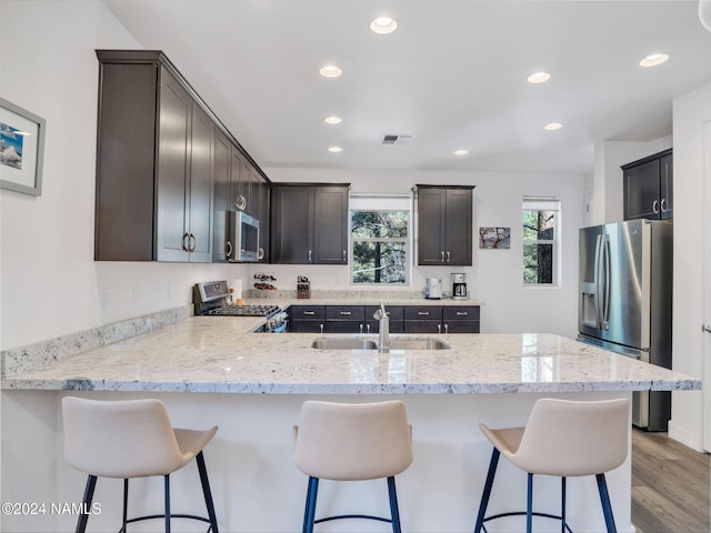 kitchen featuring sink, appliances with stainless steel finishes, kitchen peninsula, and a breakfast bar area