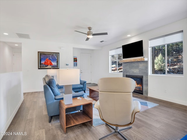 living room featuring ceiling fan, wood-type flooring, and a fireplace