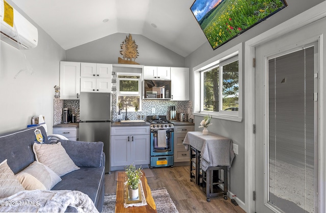 3095 E Pinetree Dr, Williams, AZ 86046 - kitchen with stainless steel appliances, a wall mounted air conditioner, dark wood-type flooring, vaulted ceiling, and tasteful backsplash