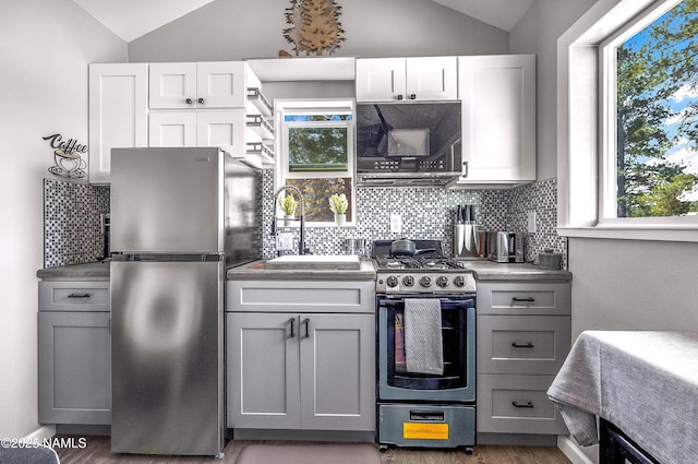 3095 E Pinetree Dr, Williams, AZ 86046 - kitchen featuring appliances with stainless steel finishes, vaulted ceiling, decorative backsplash, gray cabinets, and wood finished floors