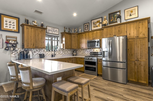 3095 E Pinetree Dr, Williams, AZ 86046 - kitchen featuring stainless steel appliances, a peninsula, a breakfast bar, decorative backsplash, and lofted ceiling