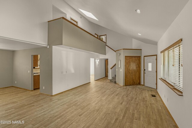 1470 W Melissa Dr, Flagstaff, AZ 86005 - unfurnished living room featuring high vaulted ceiling, stairs, light wood-style floors, a skylight, and recessed lighting