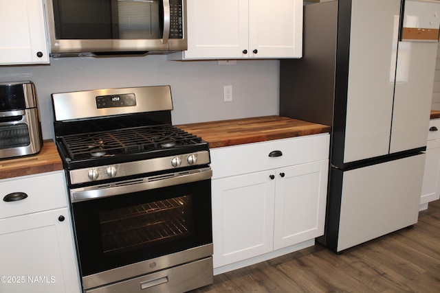 kitchen with dark wood-style flooring, butcher block countertops, appliances with stainless steel finishes, and white cabinetry