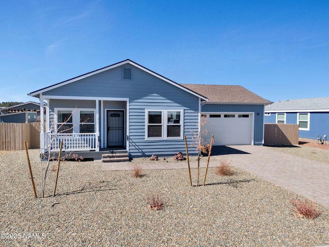 view of front facade featuring a porch, decorative driveway, fence, and an attached garage