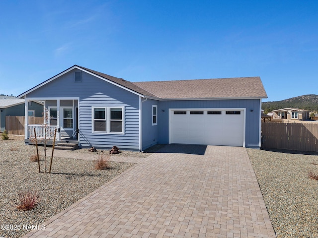 ranch-style house featuring a garage, fence, and decorative driveway