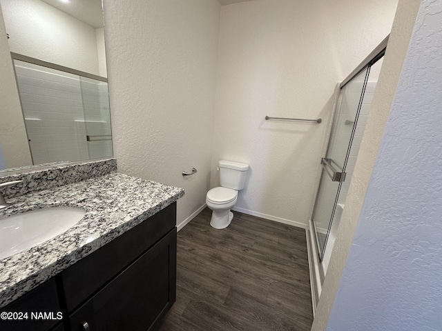 bathroom with hardwood / wood-style floors, toilet, walk in shower, and vanity