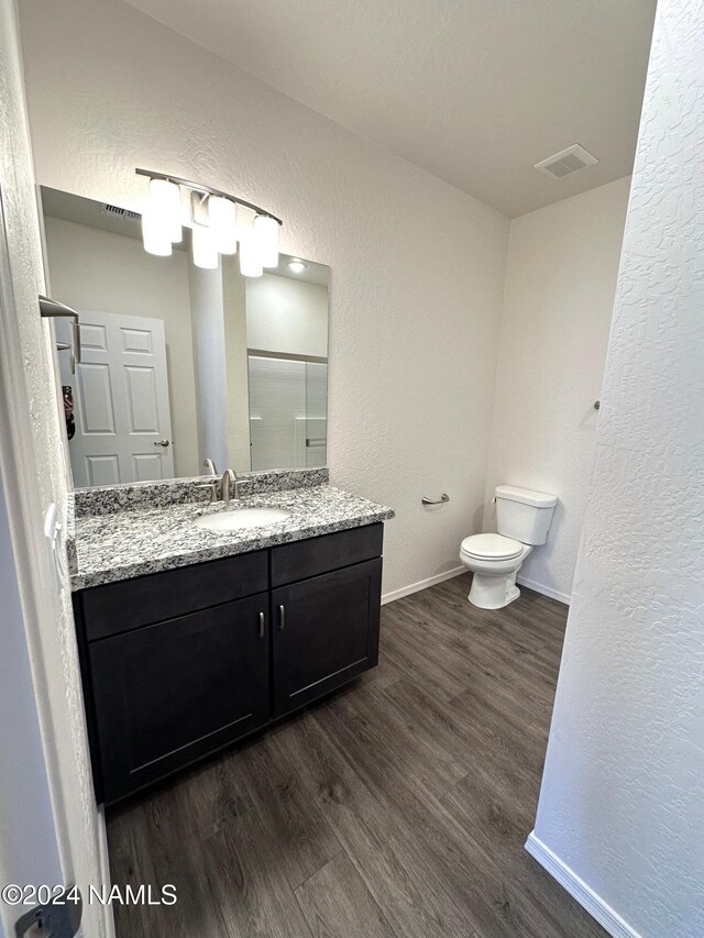 bathroom with wood-type flooring, toilet, and vanity