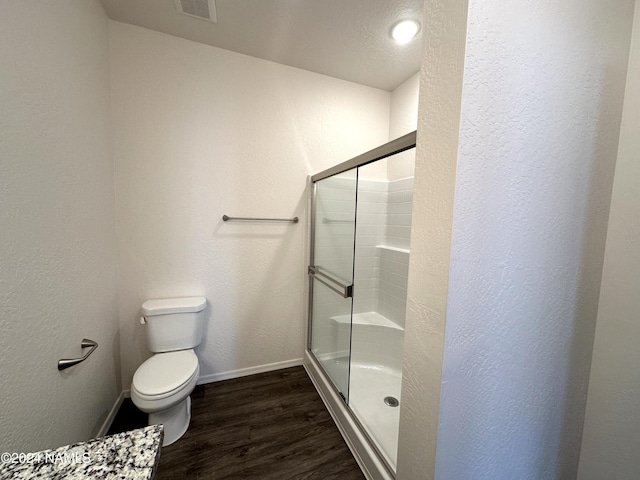 bathroom with hardwood / wood-style floors, toilet, and an enclosed shower