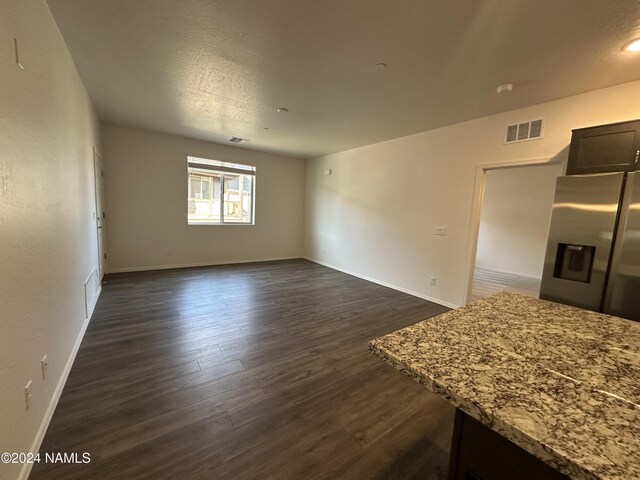 unfurnished living room featuring a textured ceiling and dark hardwood / wood-style flooring