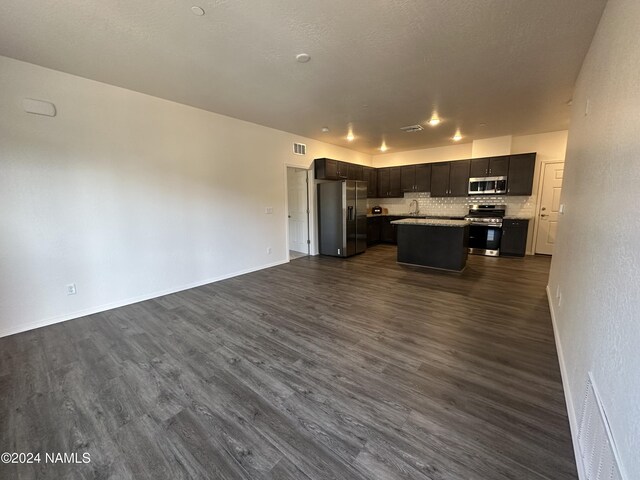 kitchen featuring a center island, appliances with stainless steel finishes, decorative backsplash, sink, and dark wood-type flooring