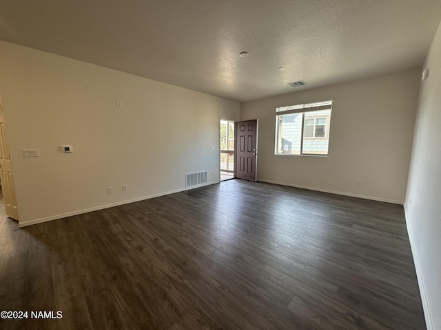 spare room featuring dark wood-type flooring and a textured ceiling