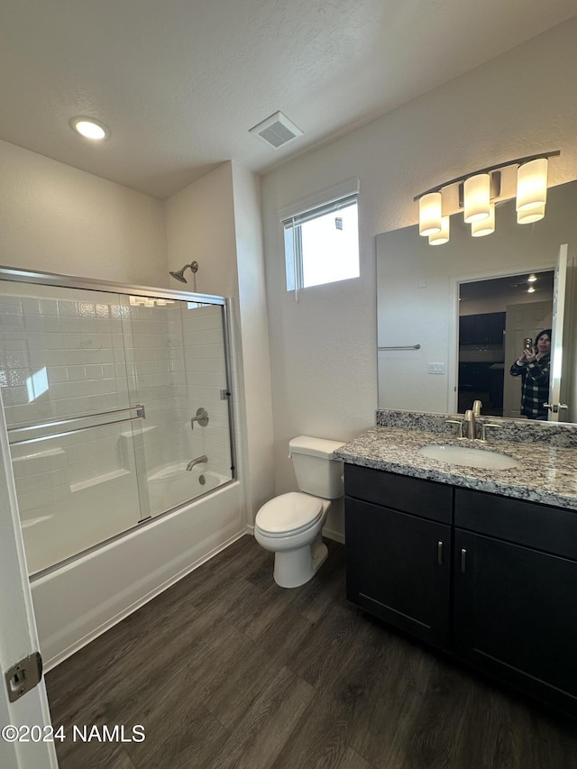 full bathroom featuring wood-type flooring, combined bath / shower with glass door, toilet, and vanity