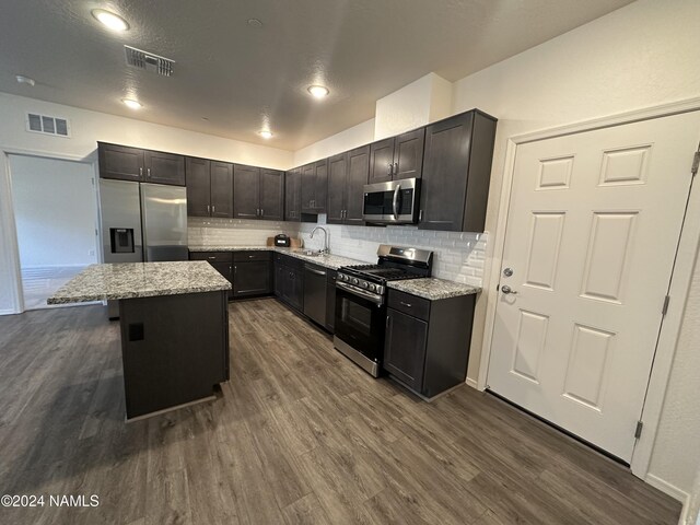 kitchen with a center island, light stone counters, appliances with stainless steel finishes, and tasteful backsplash