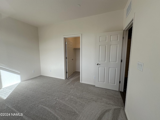 unfurnished bedroom with carpet flooring, a closet, and a walk in closet