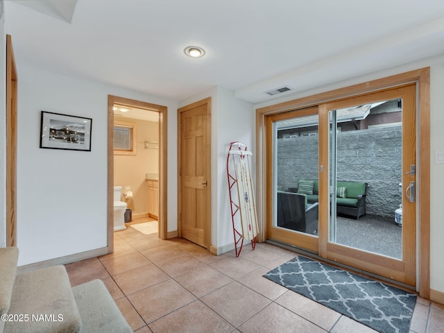 doorway to outside featuring light tile patterned floors, visible vents, and baseboards