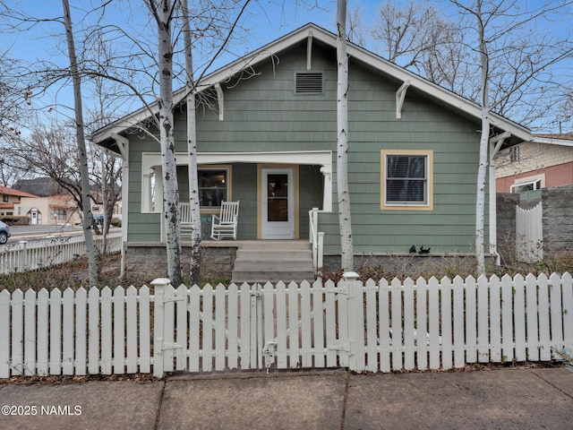 bungalow-style house with a fenced front yard and covered porch