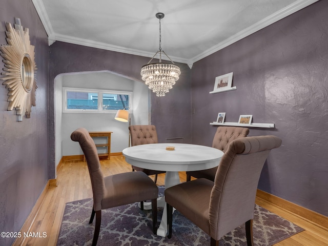 dining area featuring a chandelier, crown molding, baseboards, and wood finished floors