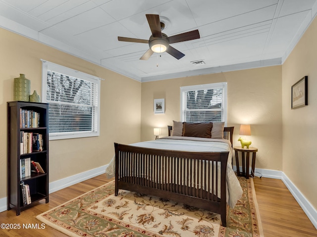 bedroom featuring multiple windows, wood finished floors, and baseboards