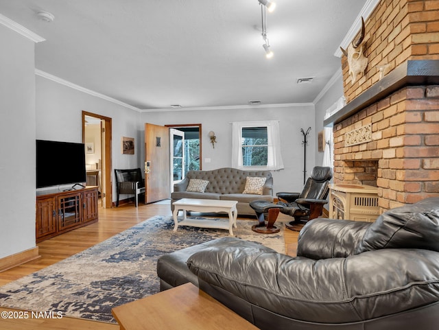 living room with light wood-style flooring, baseboards, visible vents, and ornamental molding