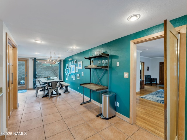 dining area with light tile patterned floors, baseboards, a chandelier, and ornamental molding