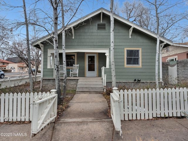 bungalow-style house with covered porch and a fenced front yard