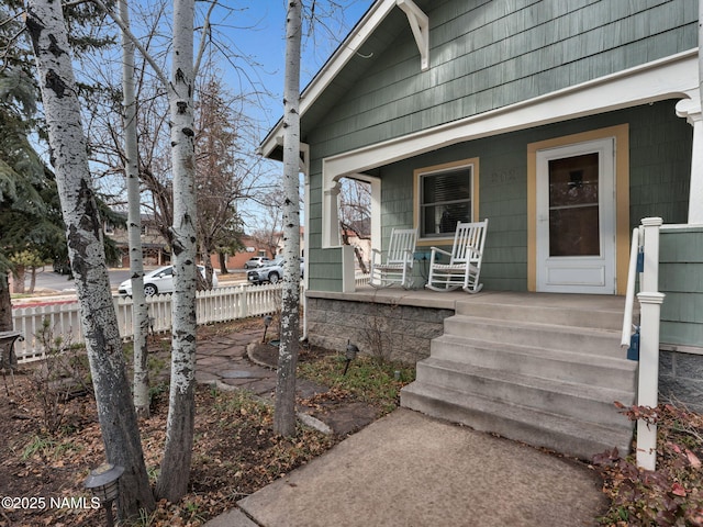 property entrance with a porch and fence