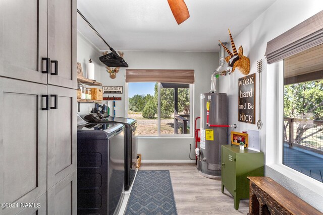 washroom with independent washer and dryer, gas water heater, cabinets, and light hardwood / wood-style flooring