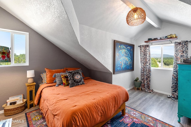 bedroom featuring hardwood / wood-style flooring, a textured ceiling, and lofted ceiling with beams