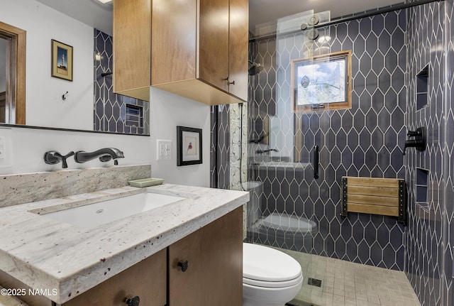 full bathroom with a tile shower, toilet, and vanity
