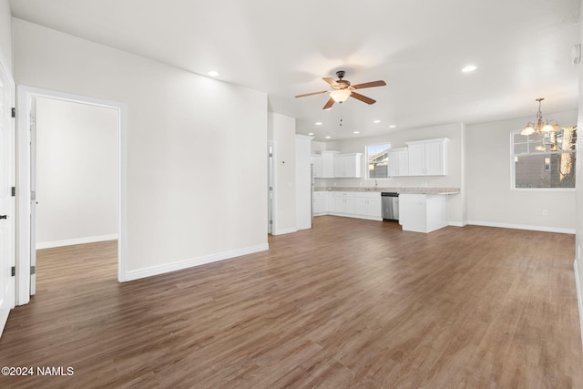 unfurnished living room featuring ceiling fan with notable chandelier and dark wood-type flooring